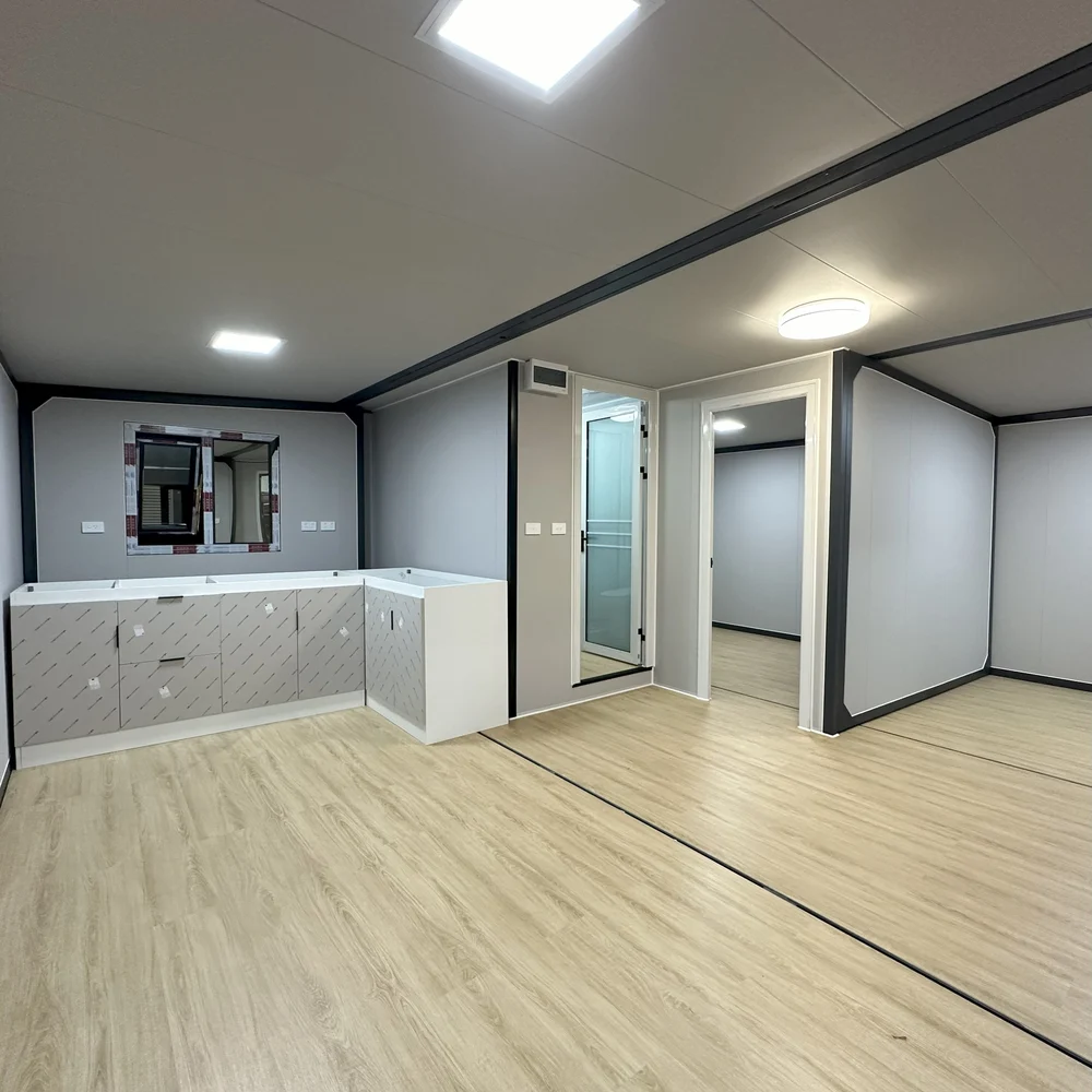 Open interior with a corner kitchen, pale flooring and doorways leading into partitioned spaces.