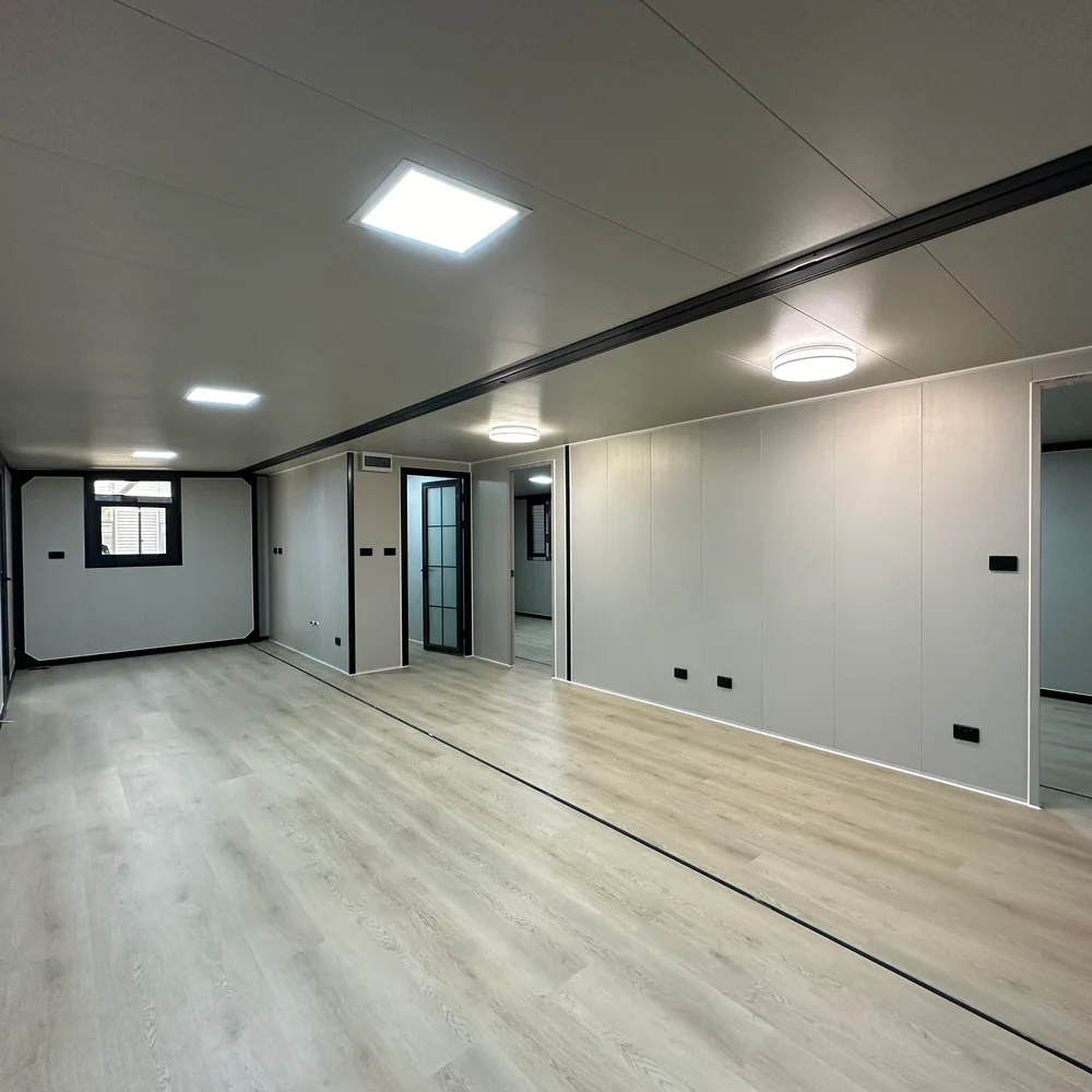 Long open interior with pale flooring, ceiling lights and several doorways along one side.