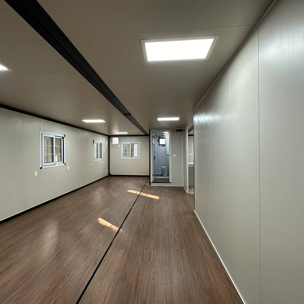 Long open interior with side windows, dark ceiling framing and a doorway at the far end.