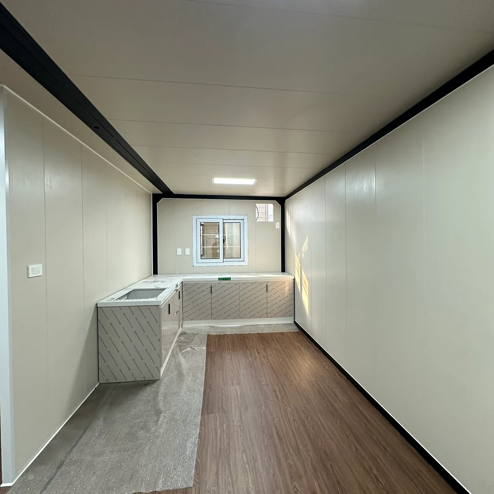 Unfurnished interior with a corner kitchen, sink, rear window and brown wood-look flooring.
