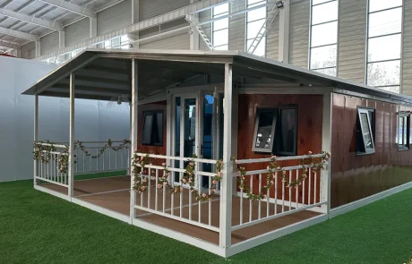 Wood-effect expandable home with a white-frame veranda and pitched roof extending over the house and veranda.