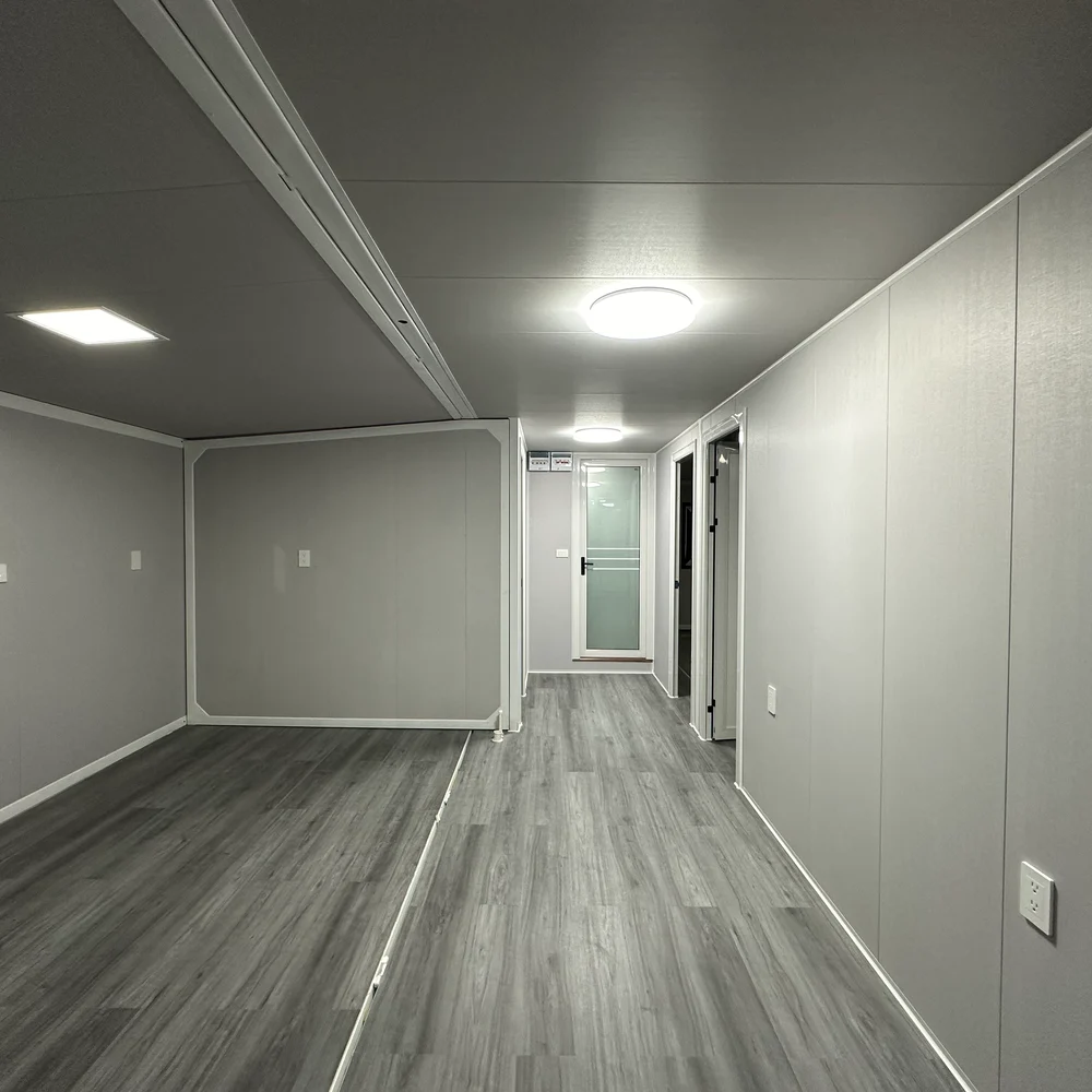 Long unfurnished interior with grey wood-look flooring and a doorway at the far end.