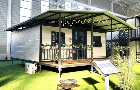 Light-coloured expandable home with a black-frame veranda and pitched roof extending over the house and veranda.