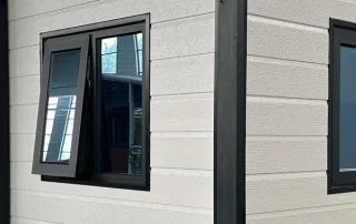 Regular-size dark aluminium window with one awning sash open outward.