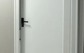 White bedroom door with a black lever handle and keys in the lock.
