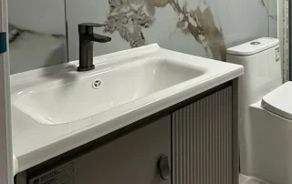 White washbasin and ribbed vanity cabinet with a black mixer tap.