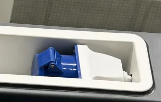 Blue external electrical inlet in a recessed white housing.