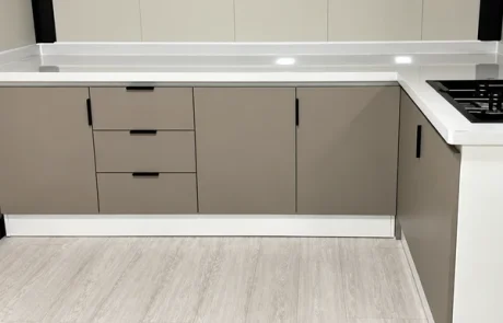 Taupe kitchen base cabinets and drawers below a pale worktop.