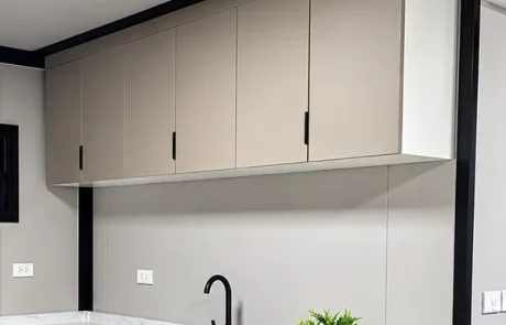Warm grey kitchen wall cabinets with slim dark handles.