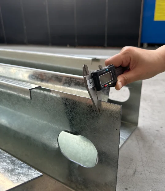 Caliper measuring the edge of a steel frame component.