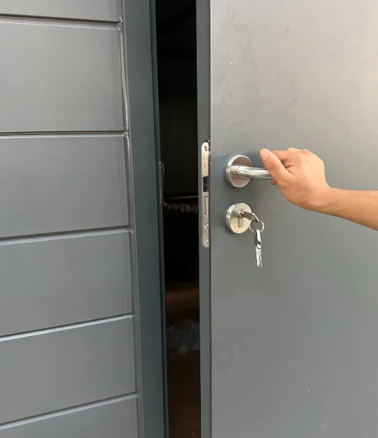 Hand operating an entrance-door handle and lock.