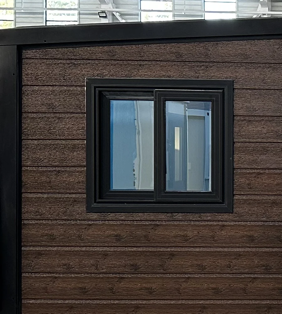 Black-framed thermal-break sliding window on an expandable home with brown exterior cladding, upgrade WN-T01.
